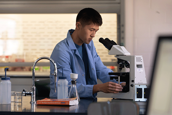 Student in the lab using a microscope