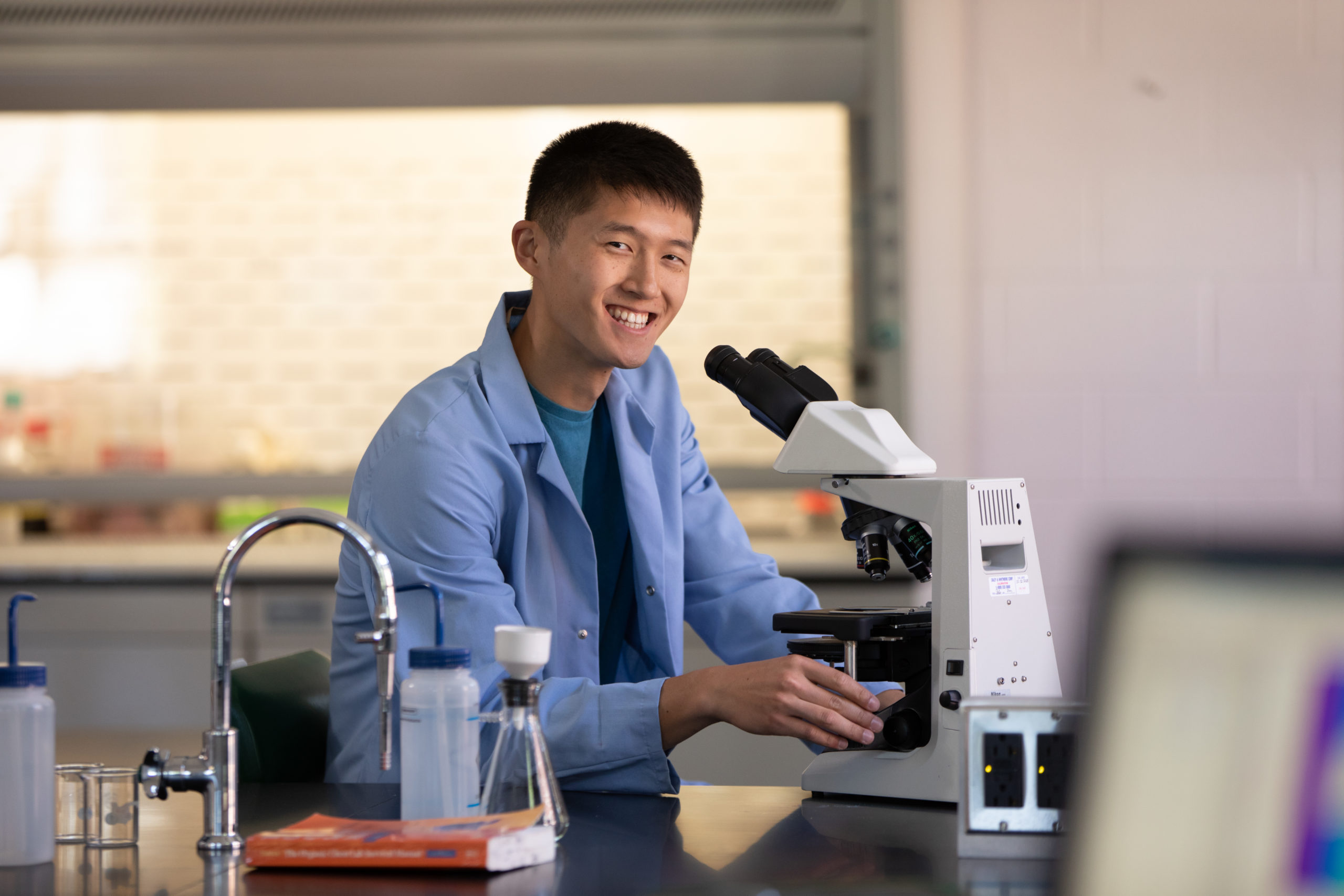 student with microscope earning biology degree